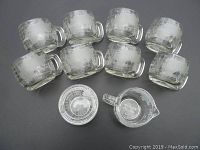 Eight clear glass coffee mugs with etched world globe designs along with matching creamer and sugar bowl with lid from the 1970s Nestle Nescafe set.