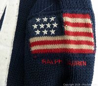 Close-up of sleeve patch showing American flag and Ralph Lauren embroidery on navy blue knit sweater.