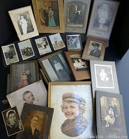Overview of various vintage portraits and photos of individuals and couples in different sized frames and mounts including children and adults, wedding attire and military dress