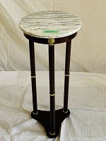 Full upright view showing round faux marble top and three-legged wooden base with gold accents.