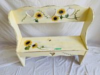 Photo of a pale yellow wooden bench, 33" H x 36" W x 11" D, with hand-painted sunflowers on the seat and backrest. The backrest has three heart-shaped cutouts and green vine accents.