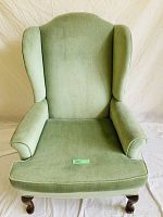Front view of the green upholstered wing chair showing the wingback design and cushioned seat.