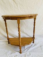 Front angled view of the wooden half moon side table showing top and lower shelf with turned spindle legs.
