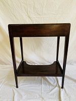 Wooden table stand front view showing lower shelf with concave cut-out and four legs.