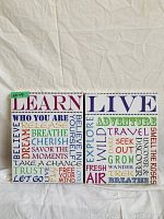 Photo of two canvas art pieces side by side on a white cloth background. One titled 'Learn' and the other 'Live' each with colorful text art.