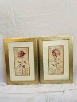 Two framed floral art prints with gold-toned frames and white mats, each approx 16" H x 11" W, featuring flowers and French text in background.