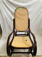 Front view of wood and cane rocking chair with a woven cane back and seat. Shows chair's height and structural integrity.