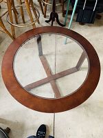 Top view of the round glass top coffee table showing the circular glass inset and wooden frame.