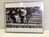 Photo of an in-ring wrestling moment featuring Mick Foley, signed by Mick Foley in black marker.