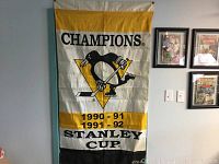 Full view of the Pittsburgh Penguins Stanley Cup championship banner for 1990-91 and 1991-92 seasons hung on a wall, showing team logo and championship text.