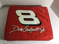 Photo of red NASCAR seat cushion with large number 8 and Dale Earnhardt Jr. signature on top.