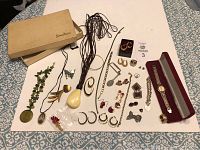 Full view of all vintage jewelry items including necklaces, rings, bracelets, pins, earrings, and watch on white cloth with Neiman Marcus box in background.