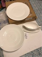 Set showing gravy boat on saucer, ornamental platter, and large plates with concentric rings, displayed on patterned surface with boxes.