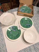 Overview of green lunch plates, white dinner plates, and cereal bowl on table