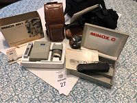 Wide shot displaying all items including Minox C, Minox ME-1 flash, brown leather Ricoh camera case, black night vision case