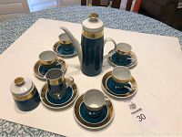 Full view of teal coffee/tea service set arranged to show all pieces: tall coffee pot, sugar bowl, creamer, 5 cups on saucers, 1 extra saucer