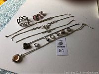 Photo showing 6 rings with stones and mixed metal designs, five necklaces with varied chain styles, and two bracelets. One necklace missing clasp.