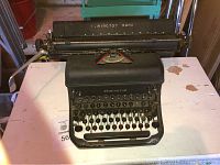 Front view of the black Remington Rand vintage typewriter showing the overall body and QWERTY keyboard with round keys.