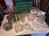 Full view of assorted clear crystal and glass pieces on table including vases, bowls, shakers, spoon set, and decanters.