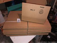 Stacked 38 flat cardboard boxes labeled 'Small LP' on a table