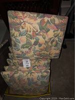 Seven folded chair covers stacked with floral and leaf tapestry fabric pattern visible.