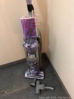 Full upright view of Shark Pet Navigator vacuum cleaner against wall with three accessories placed nearby on floor.