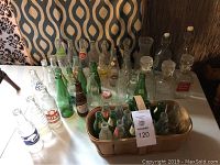 View showing assortment of vintage glass bottles including clear, green and brown bottles with some labels and embossing visible.