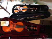 Two open zippered violin cases laid on table, each containing a violin and matching bow
