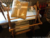 Full view of wooden blanket rack with beige throw blanket placed on top.