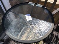 Top view of round glass-top bistro table with textured glass surface and black metal frame