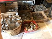 Photo showing wooden crates filled with clear glass mason jars, a wooden basket with mason jars, and a red plastic crate holding metal lids.