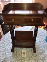 Front view of the wooden side table showing the drawer and raised edges on top.