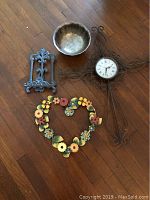 All four items in the lot shown together on the floor: scroll wall clock, cookbook stand, heart-shaped wreath, and silver plate bowl.