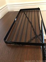 Photo of black metal rectangular hanging pot rack showing slotted design and attached hanging chains.