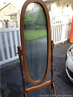 Front view of oval full length mirror on wooden stand showing the mirror surface and frame details.