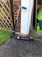 Full view of blue Metalix child's scooter showing T-bar handlebar with blue grips and lower foot deck on asphalt surface.