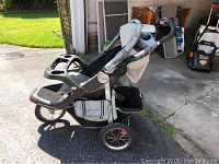 Side view of Jeep jogging stroller showing three large air-filled wheels, storage basket, and handlebar with cup holders and tray.