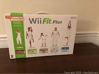 Front view of sealed Wii Fit Plus game box featuring fitness images and green promotional text.