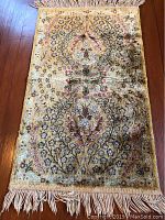 Full view of the small oriental rug displaying the floral medallion pattern and fringe on both ends.