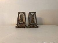Front view of the two vintage solid metal mirrored bookends side by side, showing the decorative metal frames and mirrored panels.