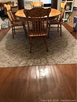 Photo showing the rug under a wooden dining table with chairs, illustrating size and pattern.