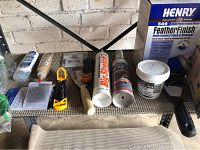 Photo showing caulk tubes, Henry FeatherFinish box, sanding tools, and screen repair supplies on a shelf against a brick wall