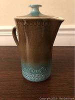 Front view of vintage coffee carafe with lid and handle, showing gradient glaze from blue to brown and decorative patterns at base and top.