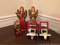 Lot items arranged on table: Murano glass amber angel, two 10-inch angels with musical instruments, two silver and red Harvey Lewis stocking holders.