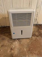 Front view of white ArcticAire dehumidifier showing intake grille and water level indicator on water tank.