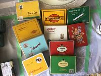 Overview of twelve assorted vintage cigarette tins with various brand names and artwork.