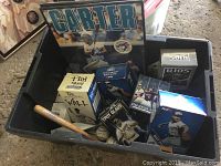 Top-down view of black bin containing boxed bobble heads, mini bat and signed baseballs
