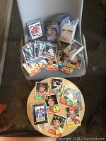 Various vintage baseball cards spread on a chair and table, including labels and sleeves