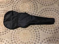 Black nylon carrying case for guitar laid flat showing shape and zipper pocket.