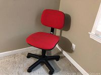 Front angle view of a red office chair showing the seat, backrest, and black caster base.